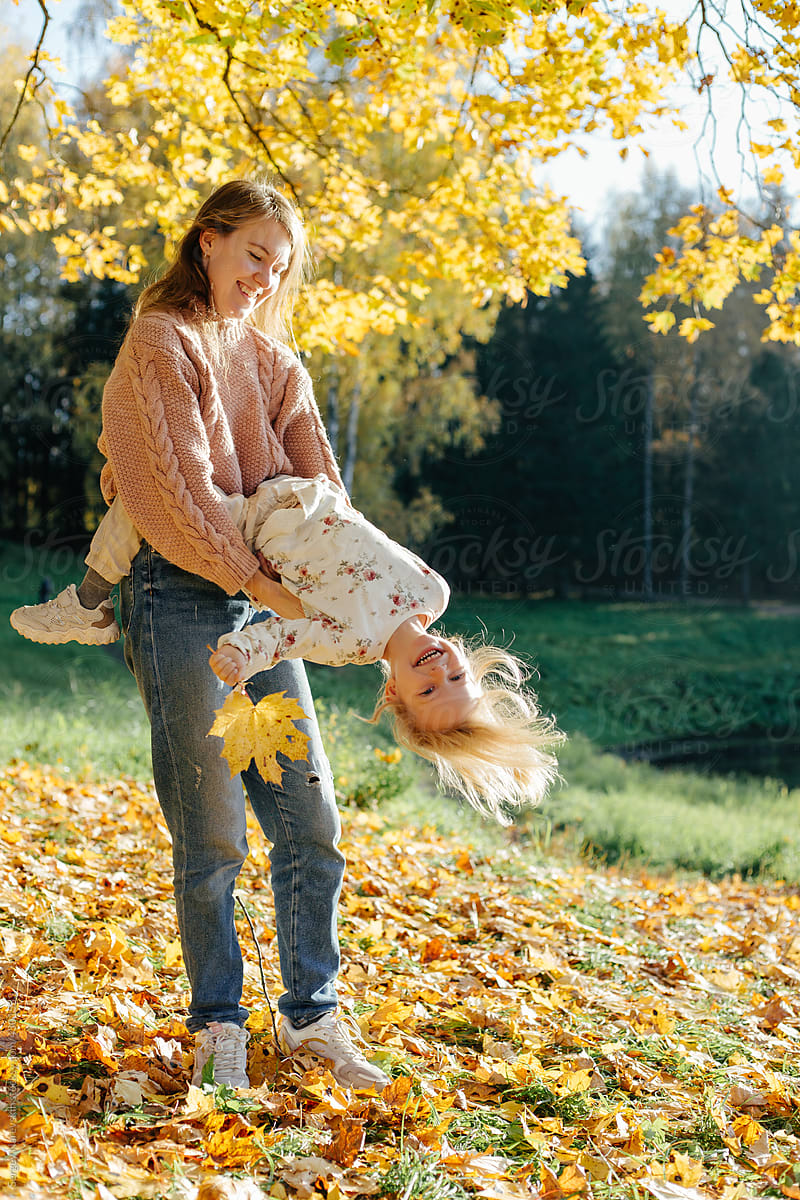 Mom and child playing under autumn tree