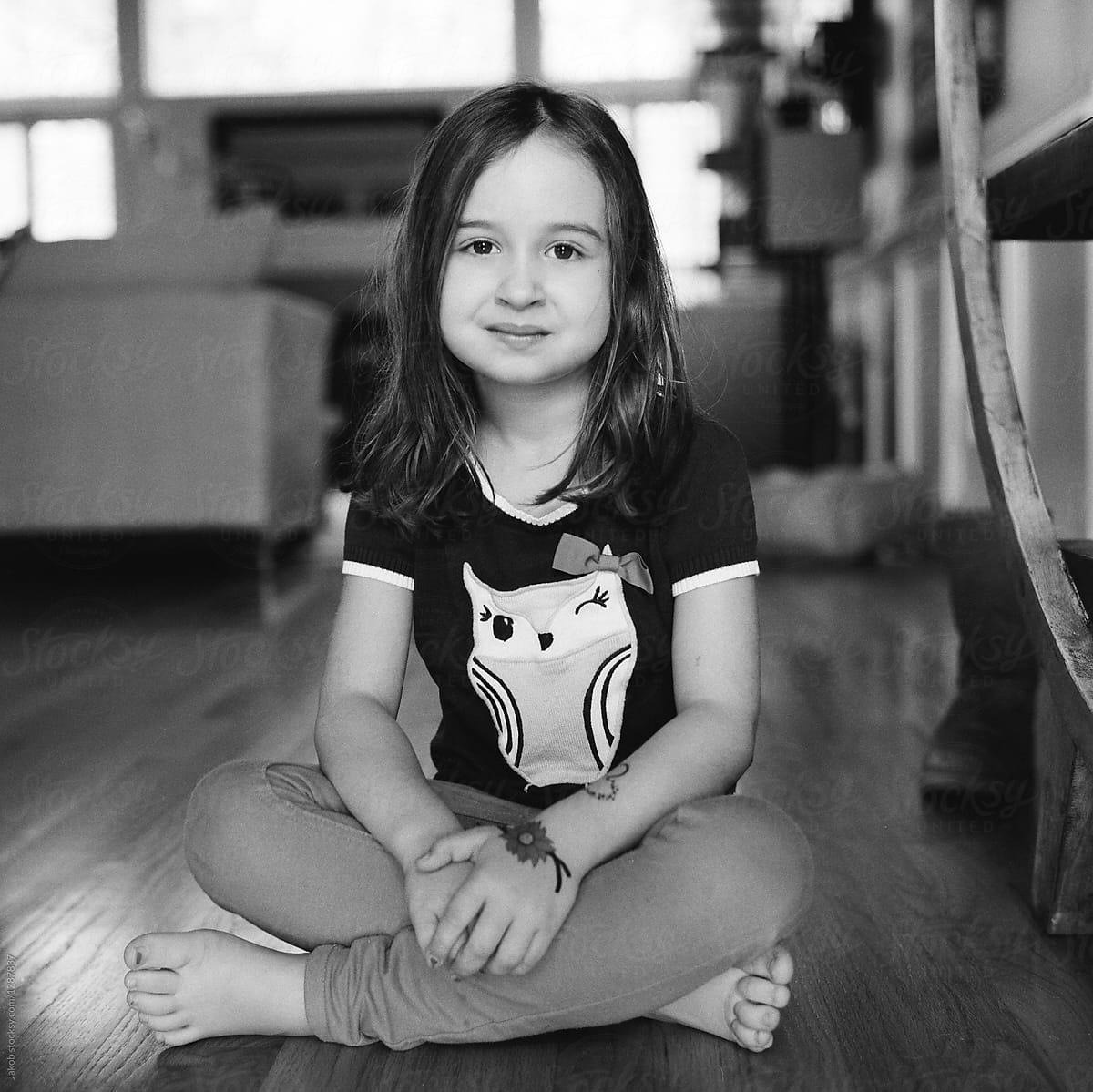 Cute Young Girl Sitting On The Floor Looking At Camera By Jakob
