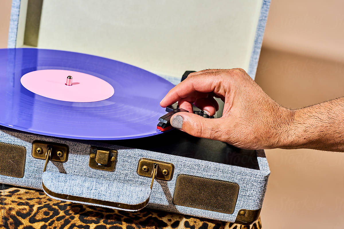 man is about to play a disc in a portable turntable