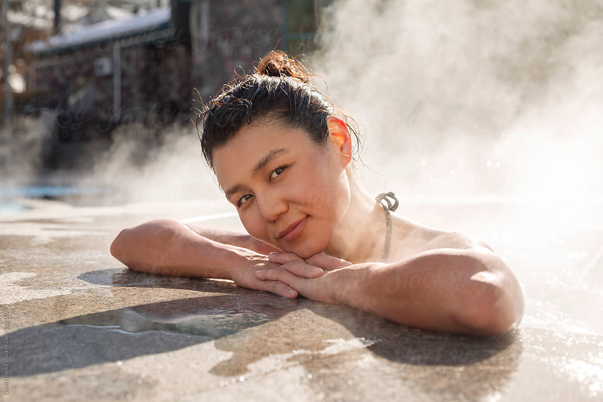 Happy lady smiling at camera in hot spring pool