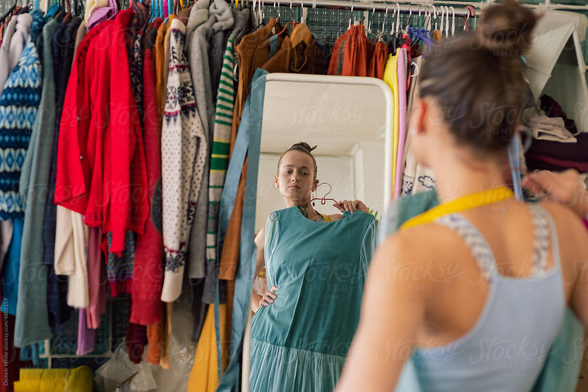 woman holds her dress to herself and looks in the mirror