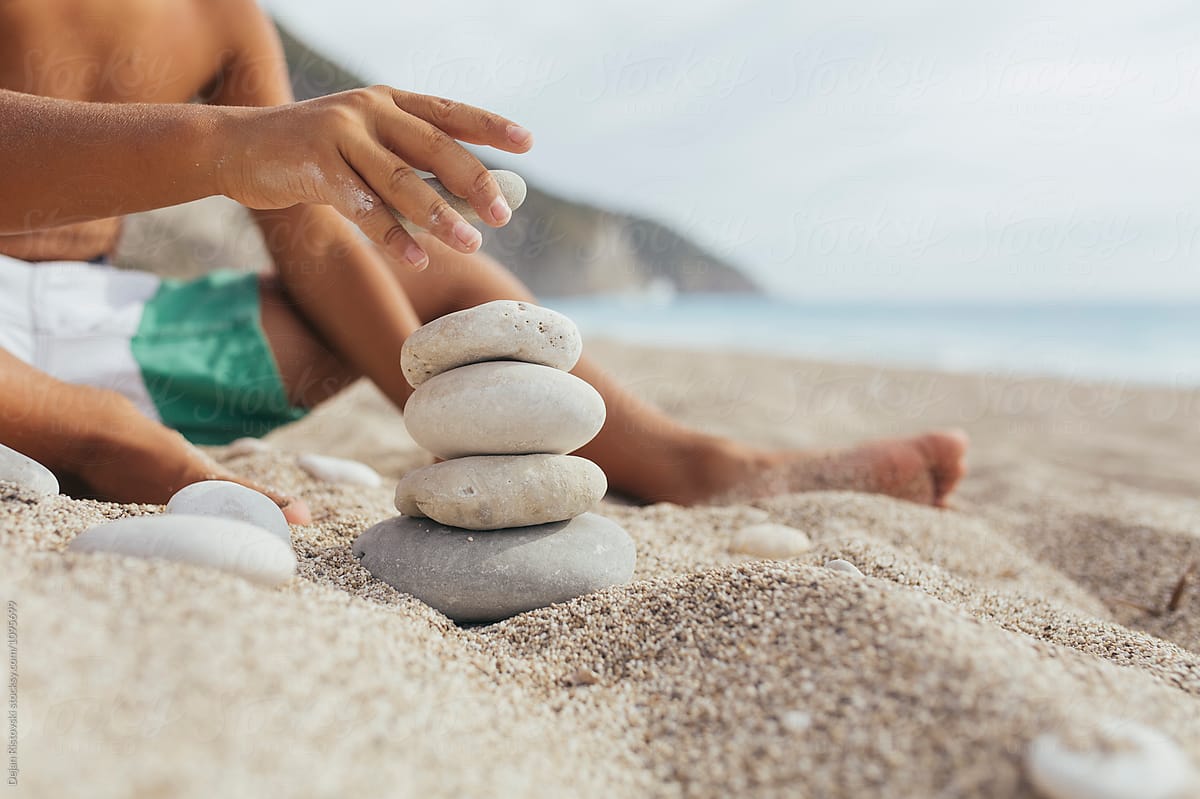 Hand making stone balance on the beach.