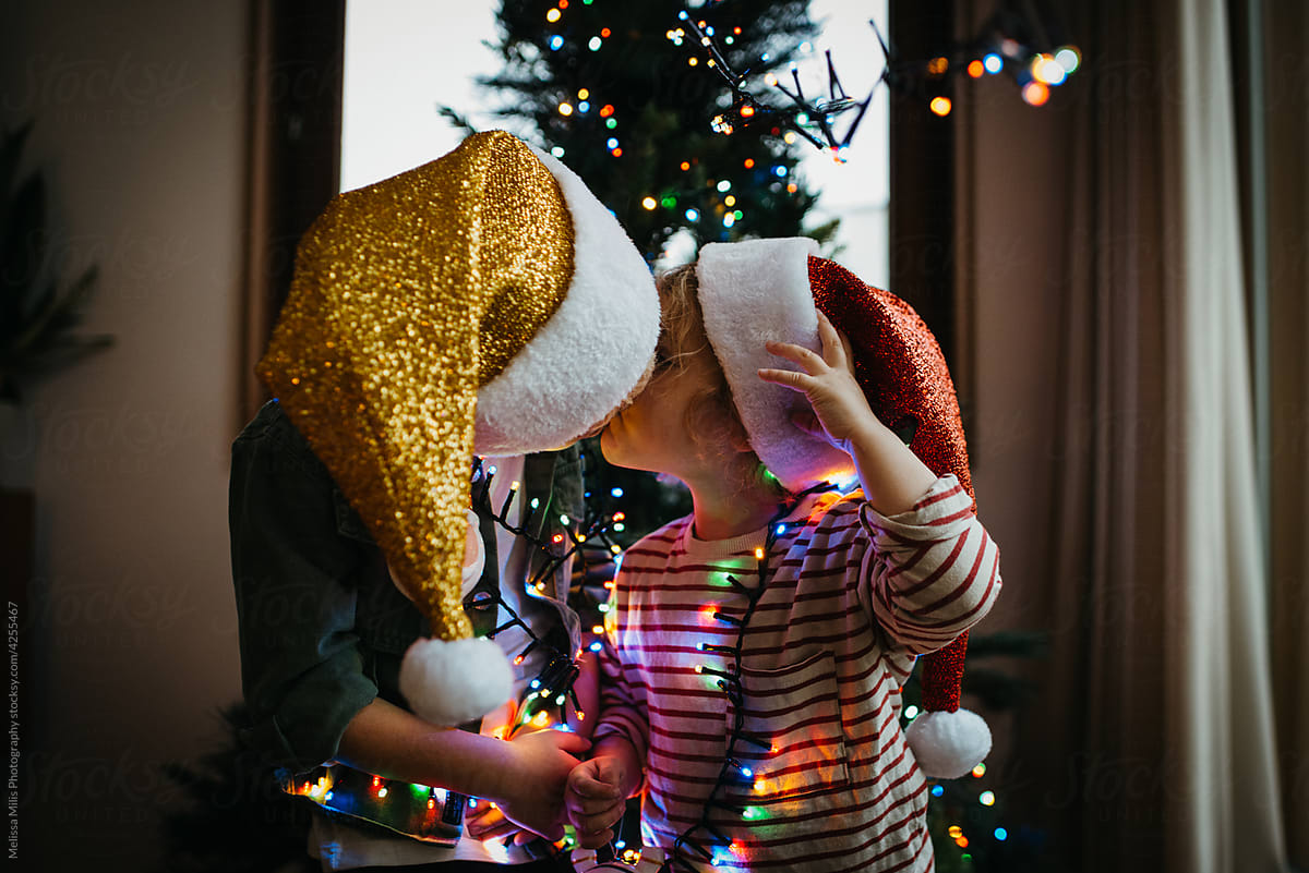 Two kids kissing in front of the Christmas tree