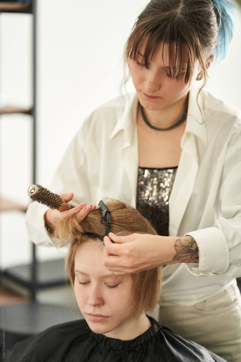 Hairdresser putting hairpin on hair of client