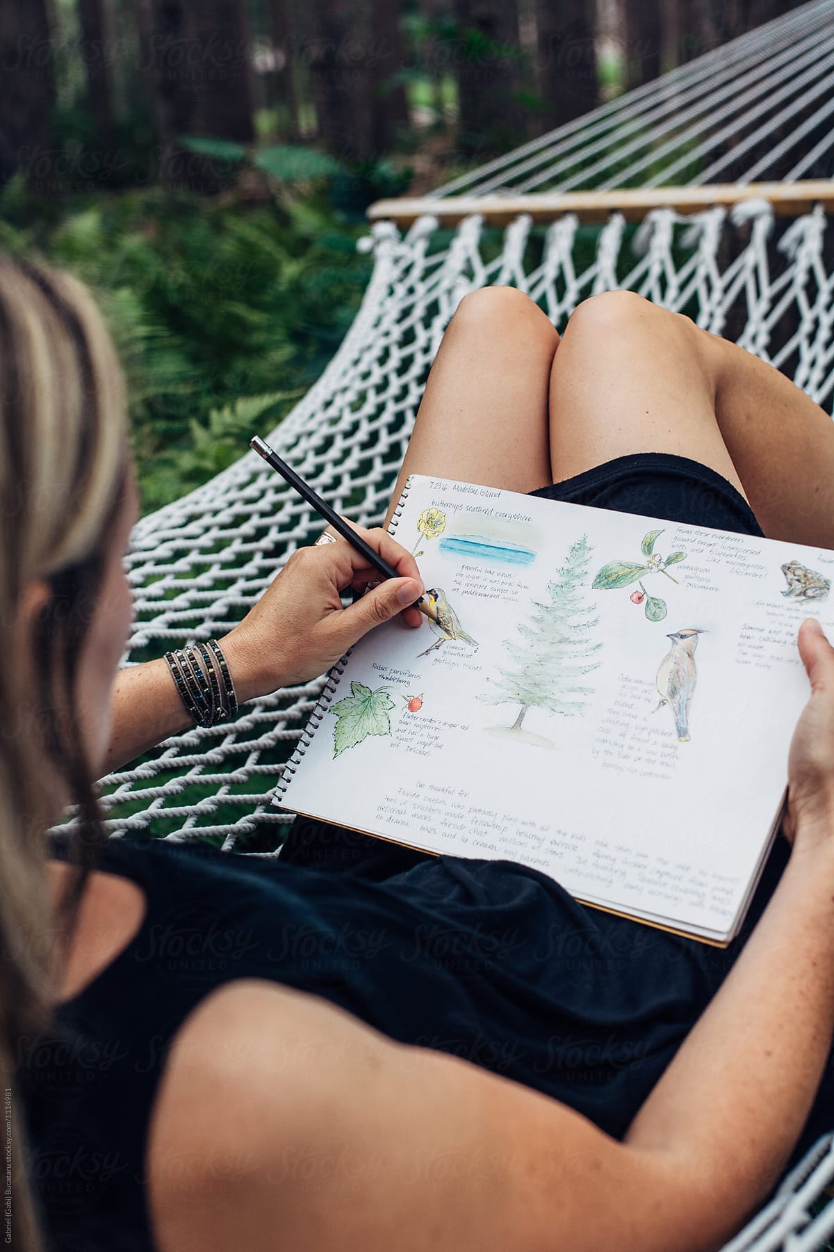 Female drawing in her nature journal on a hammock