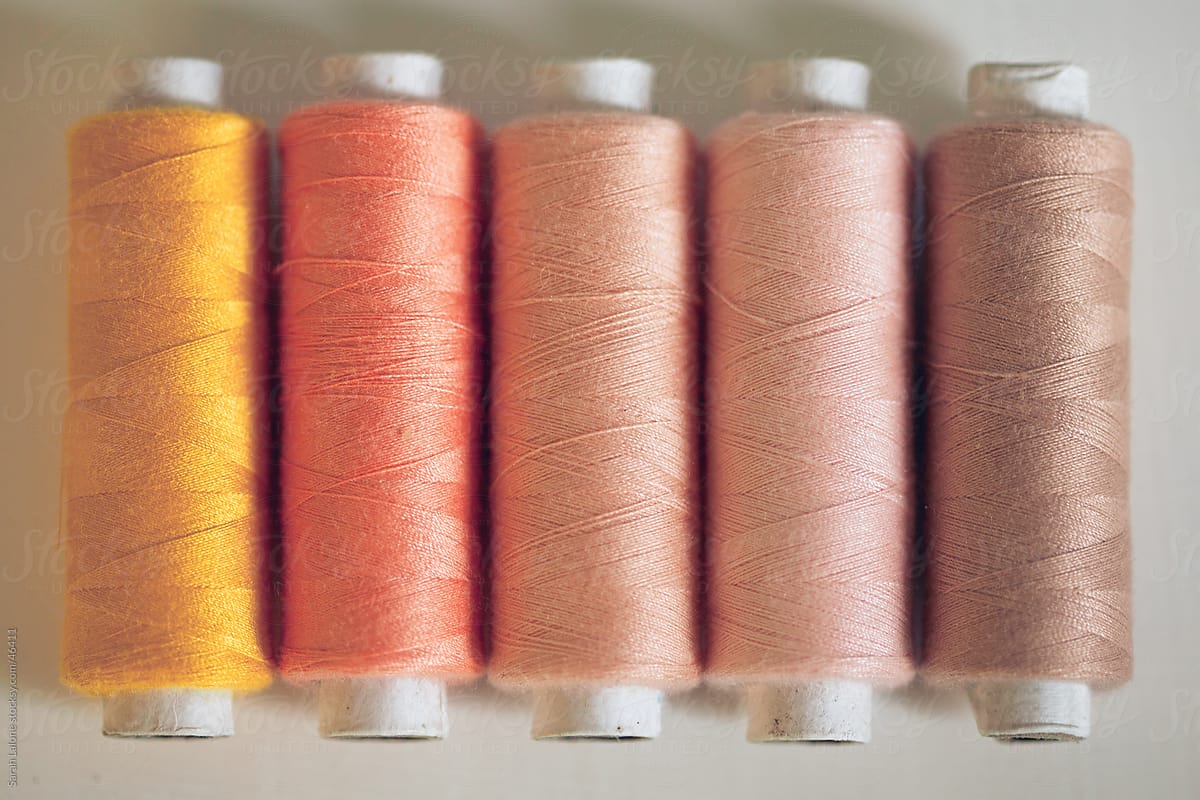 Orange and peach thread spools lined up on a table.