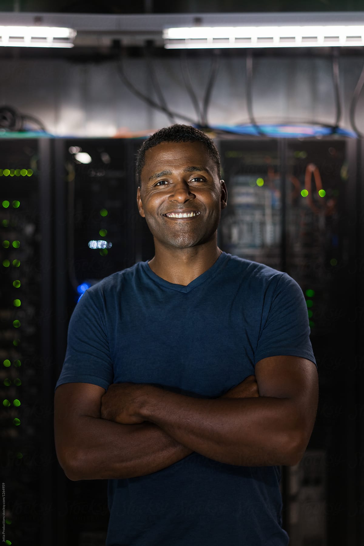 Portrait of a technician standing in front of bank of lit server