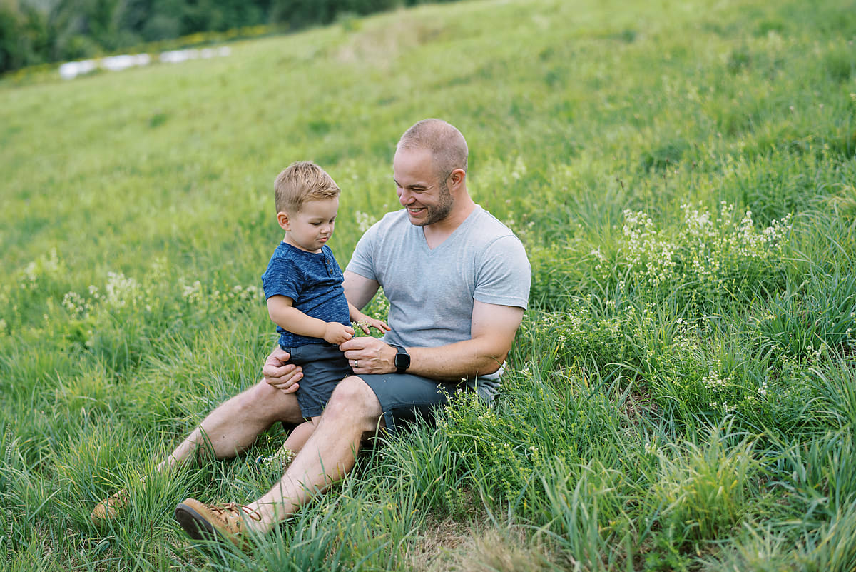 smiling father and son in grass together