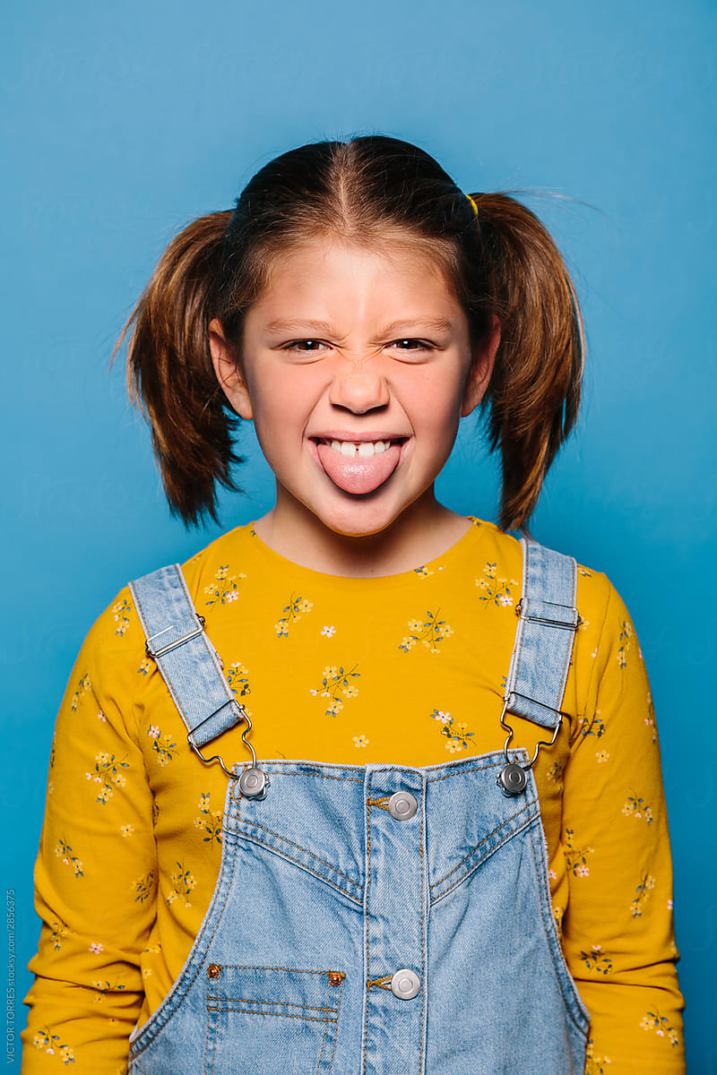 Studio Portrait Of Cute Teen Girls Sticking Out Tongue by Stocksy  Contributor VICTOR TORRES - Stocksy