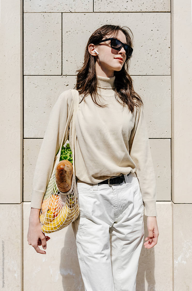 Young female with mesh bag of healthy food at city