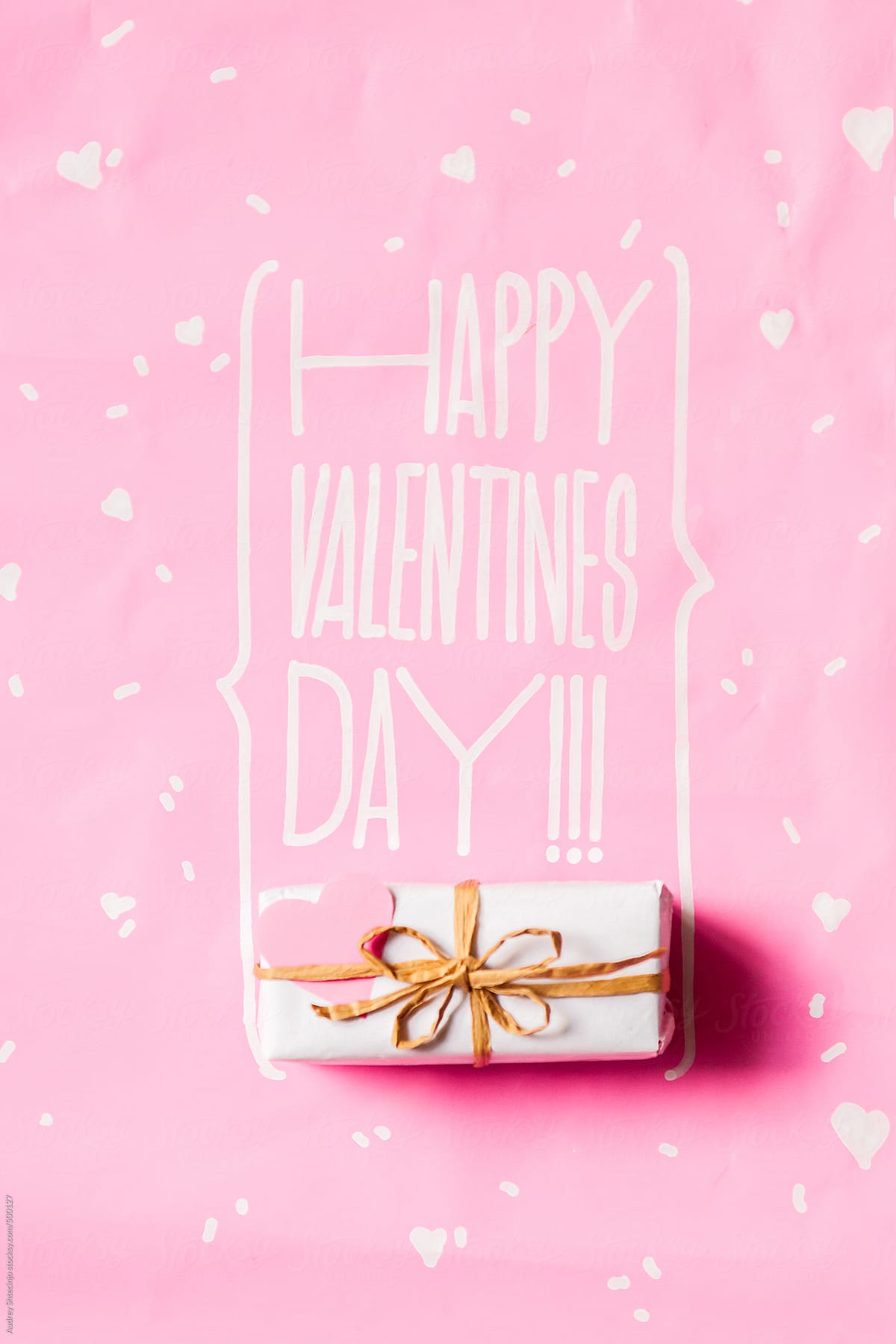 Happy Valentines Day text with present on pink background.