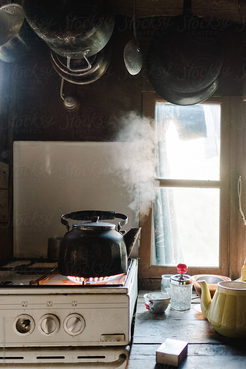 stock photo of water boiling in kettle on the gas stove in rustic kitchen
