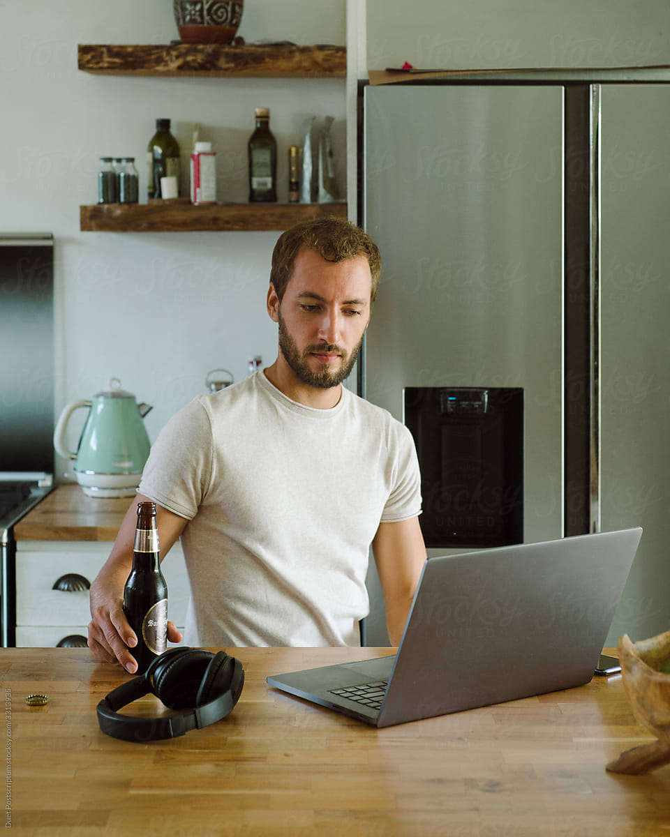 Portrait of guy with beer near laptop