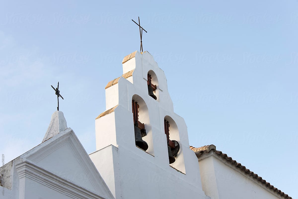 The cross and bell tower of Catholic church in Spain.