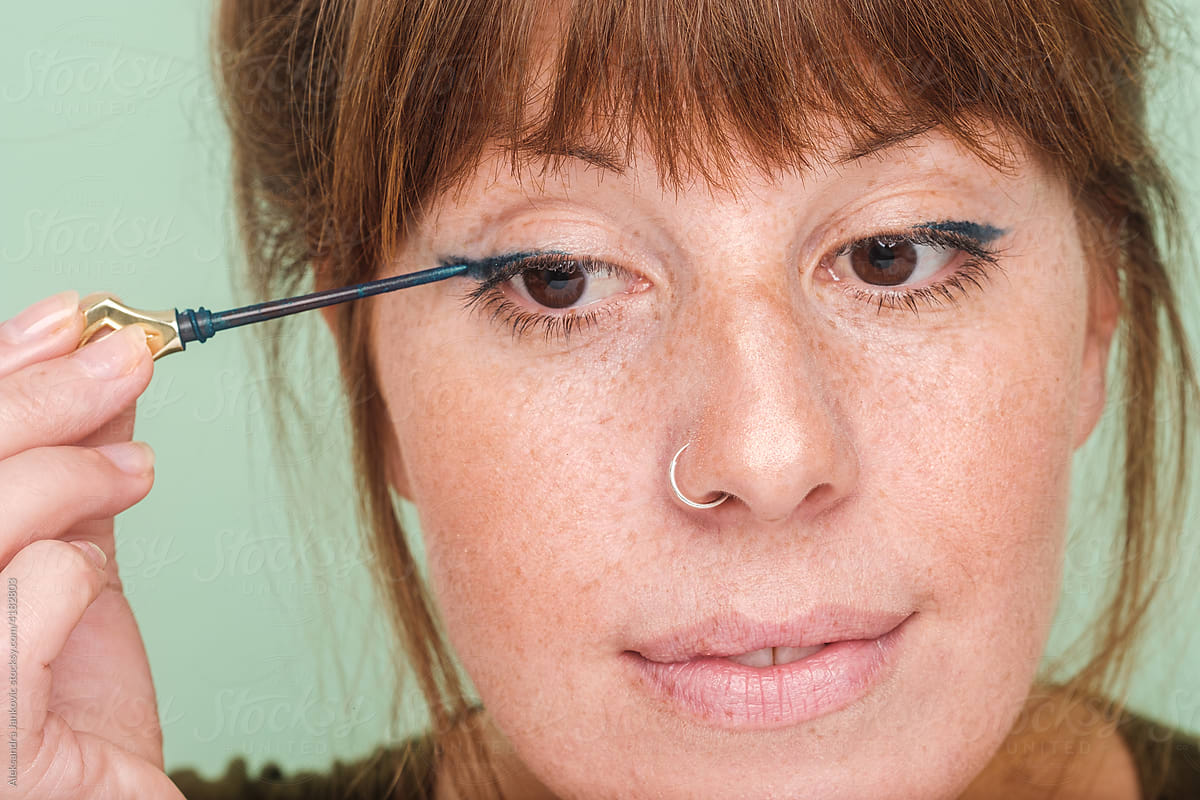 Close Up Of Ginger Woman Applying Eyeliner