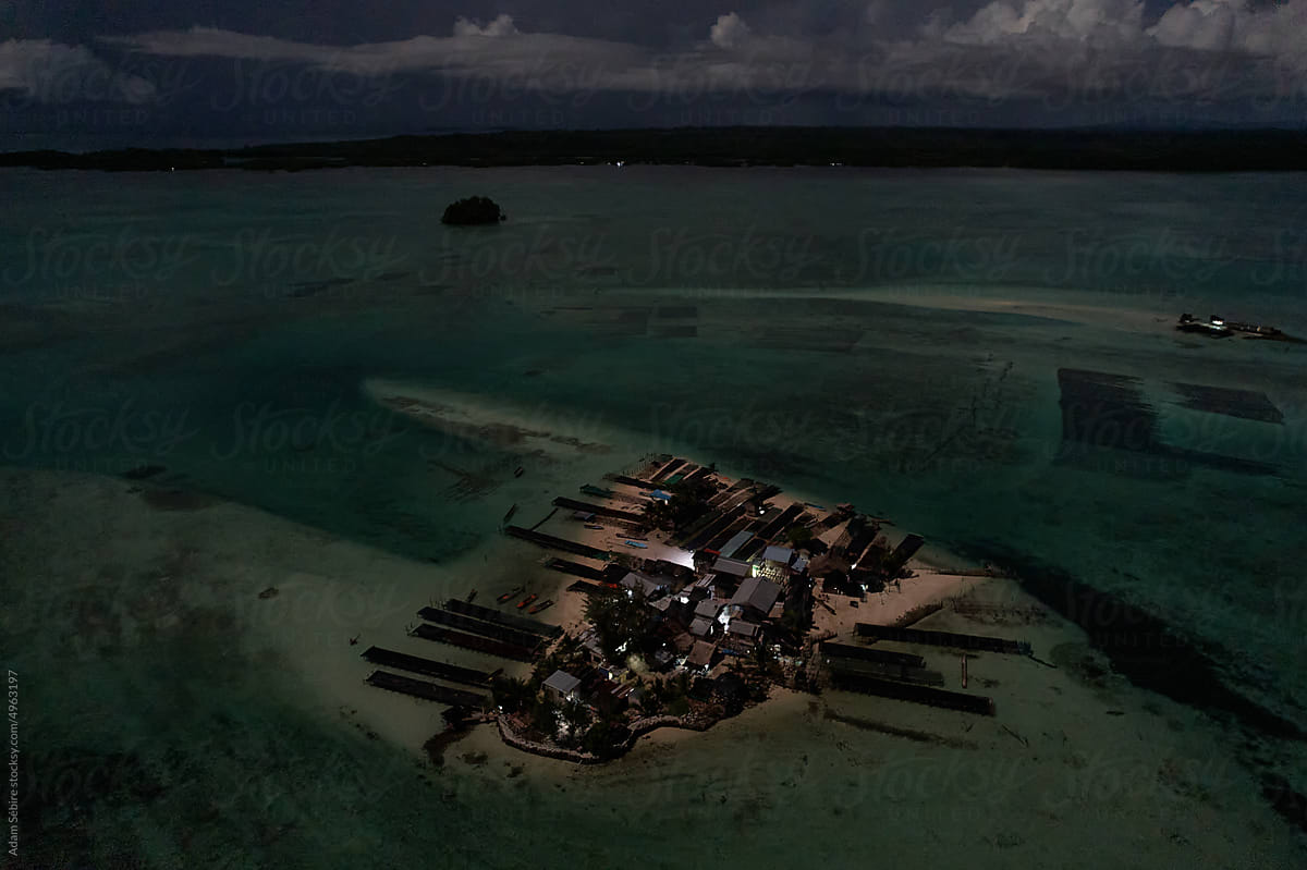 Night aerial on un-electrified Solomon islands atoll village, Pacific