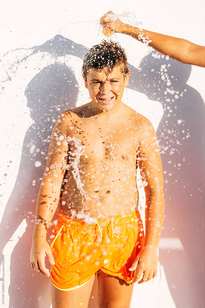 Funny kid while another person blows up a water balloon