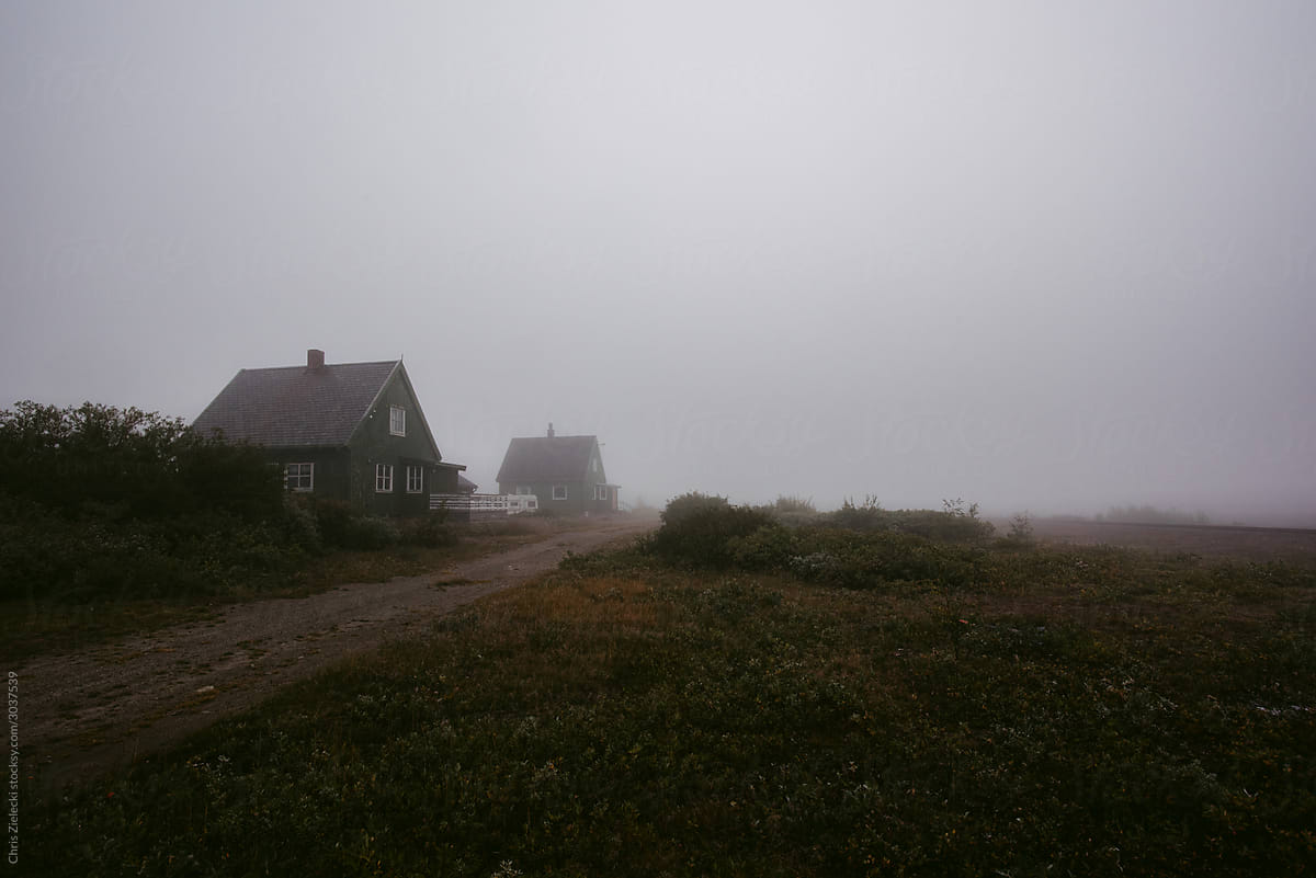 Foggy landscape with small houses and field