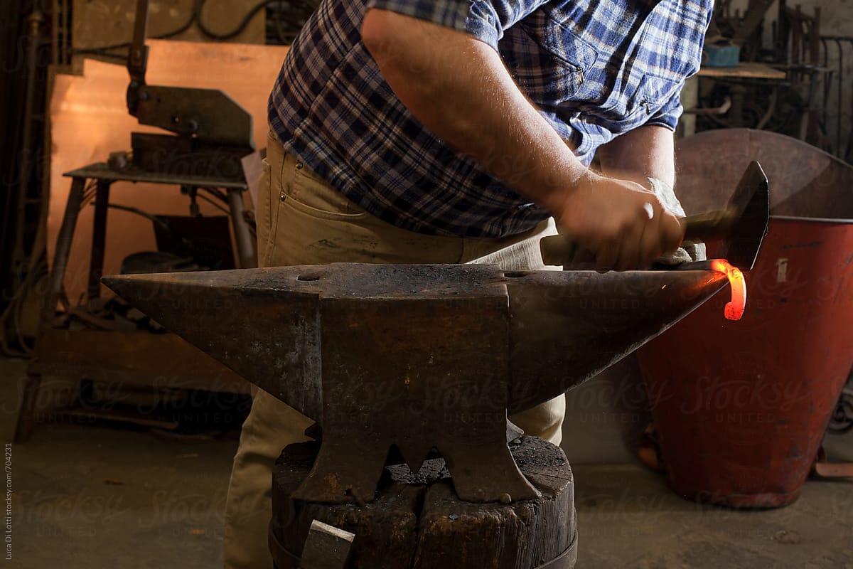 Blacksmith hammering a red-hot iron rod on an anvil