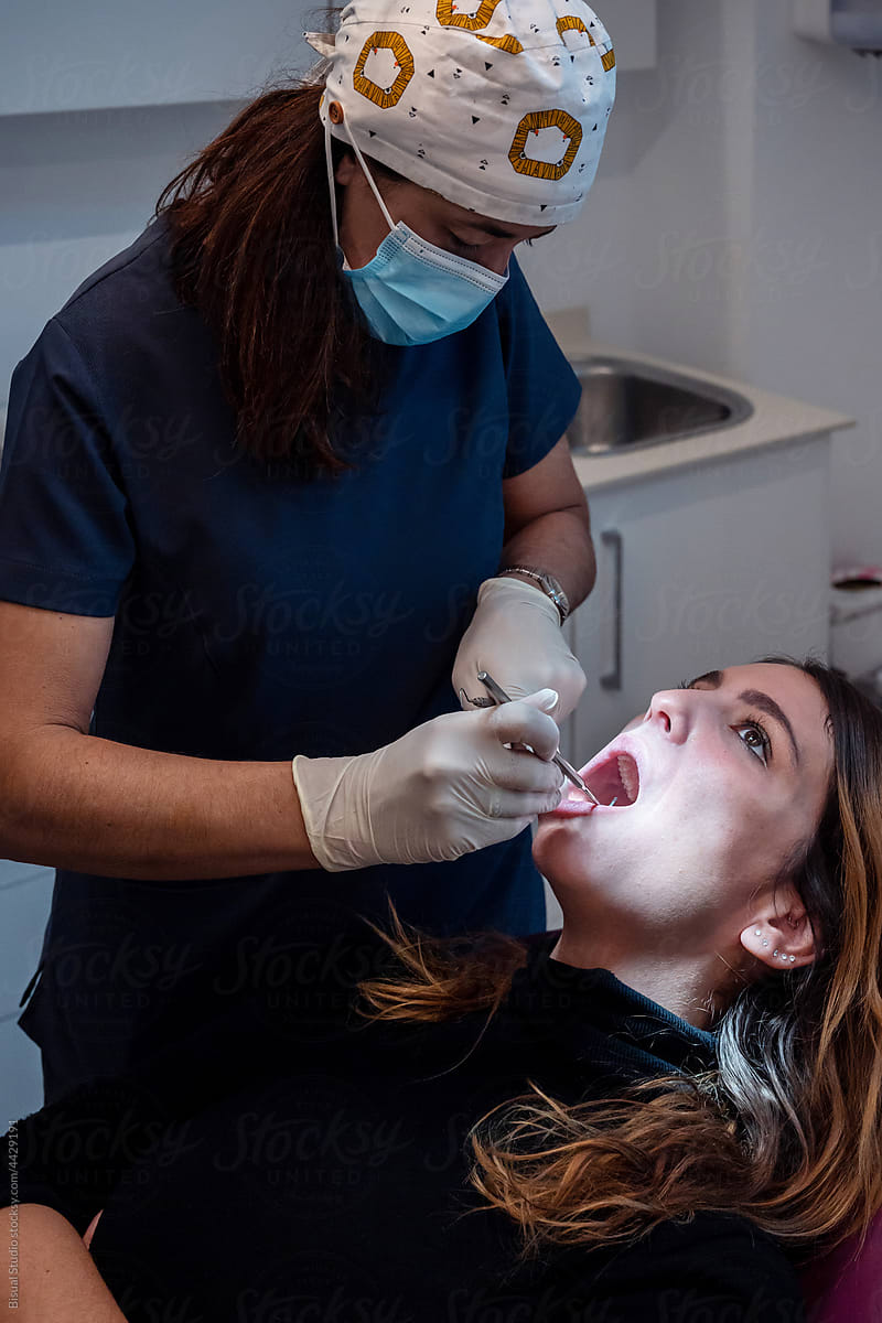 Female dentist examining gums and teeth of female client