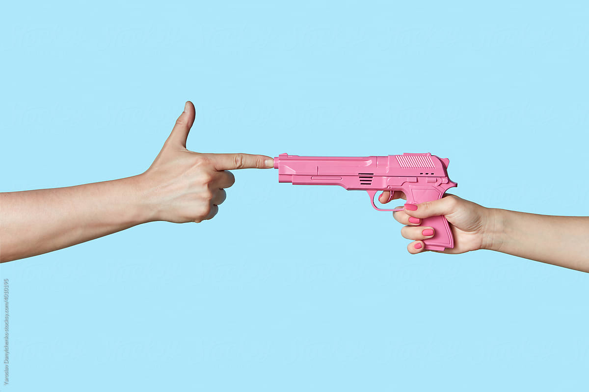 Woman pointing pink gun at hand