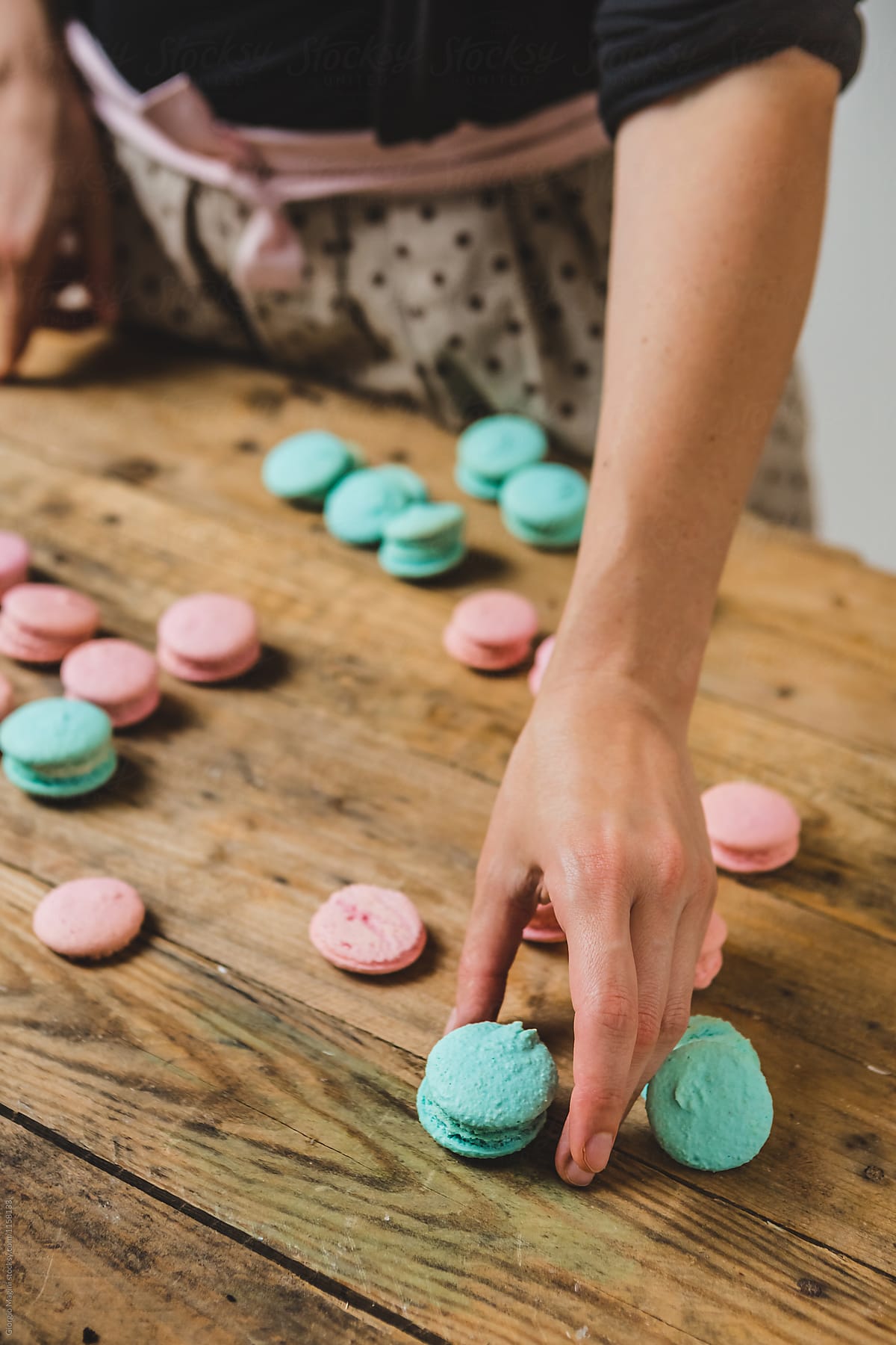 Woman Preparing Colored Macarons on a Wooden Table