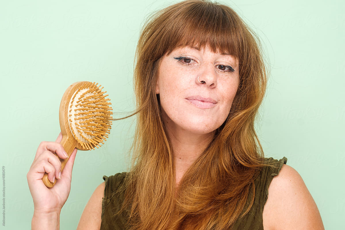 Studio Beauty Shot Of A Ginger Woman Brushing Her Hair