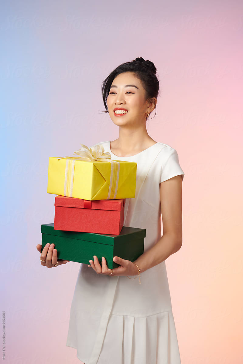 Excited pretty lady in dress holding stack of gift boxes