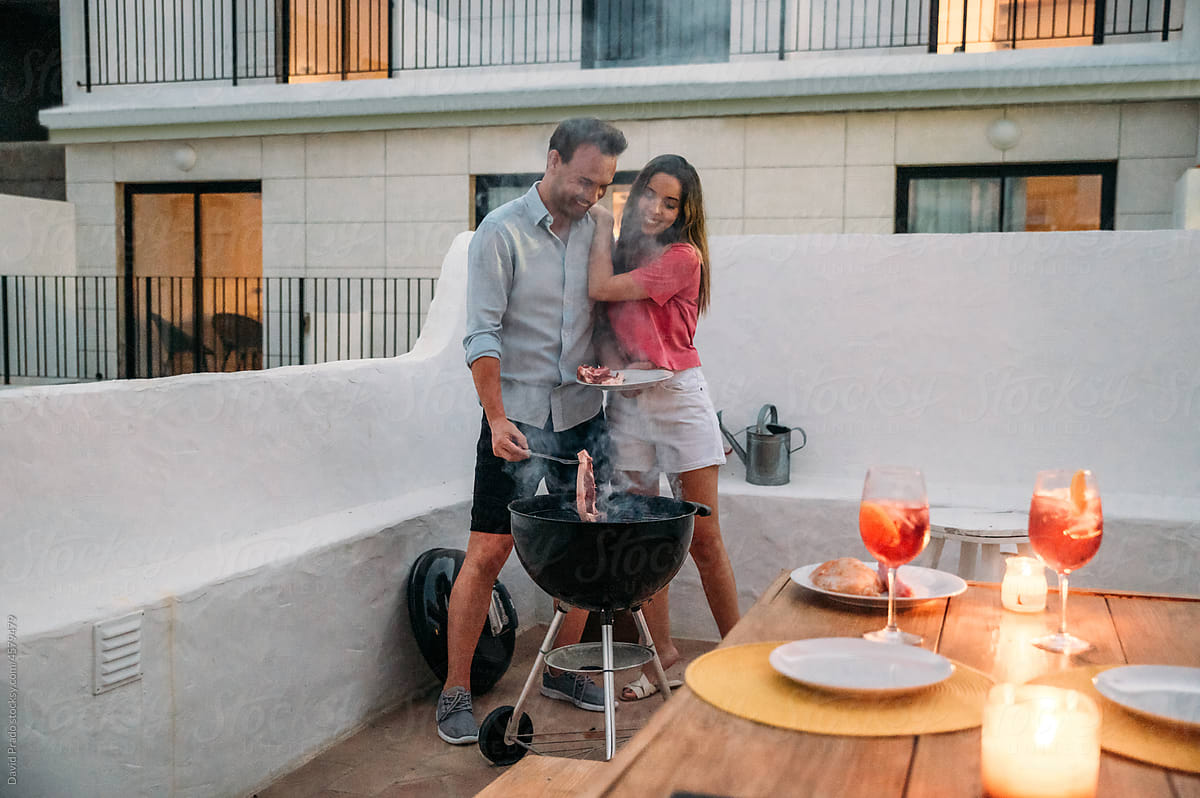 Happy couple preparing food on terrace