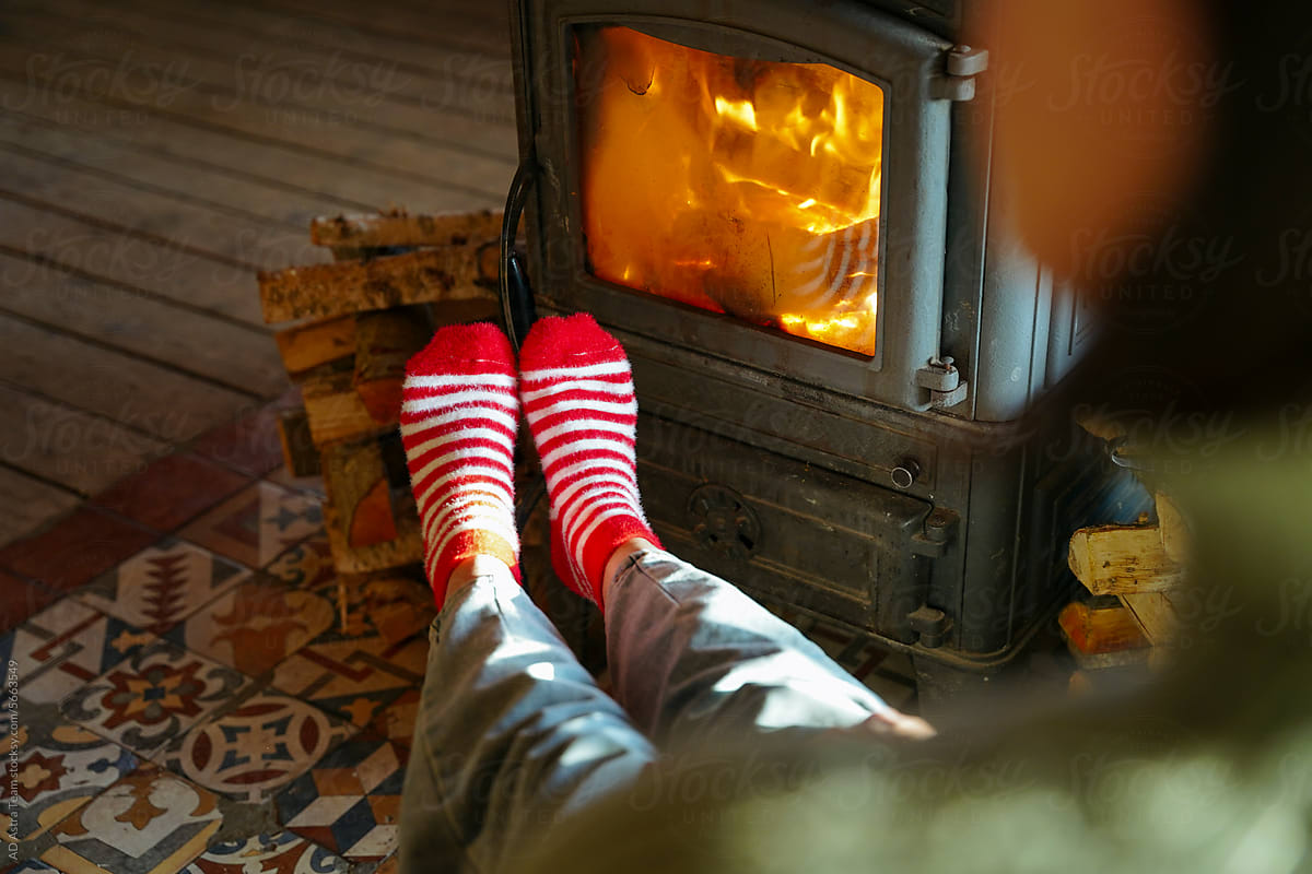 The legs of a woman in red socks are warming themselves