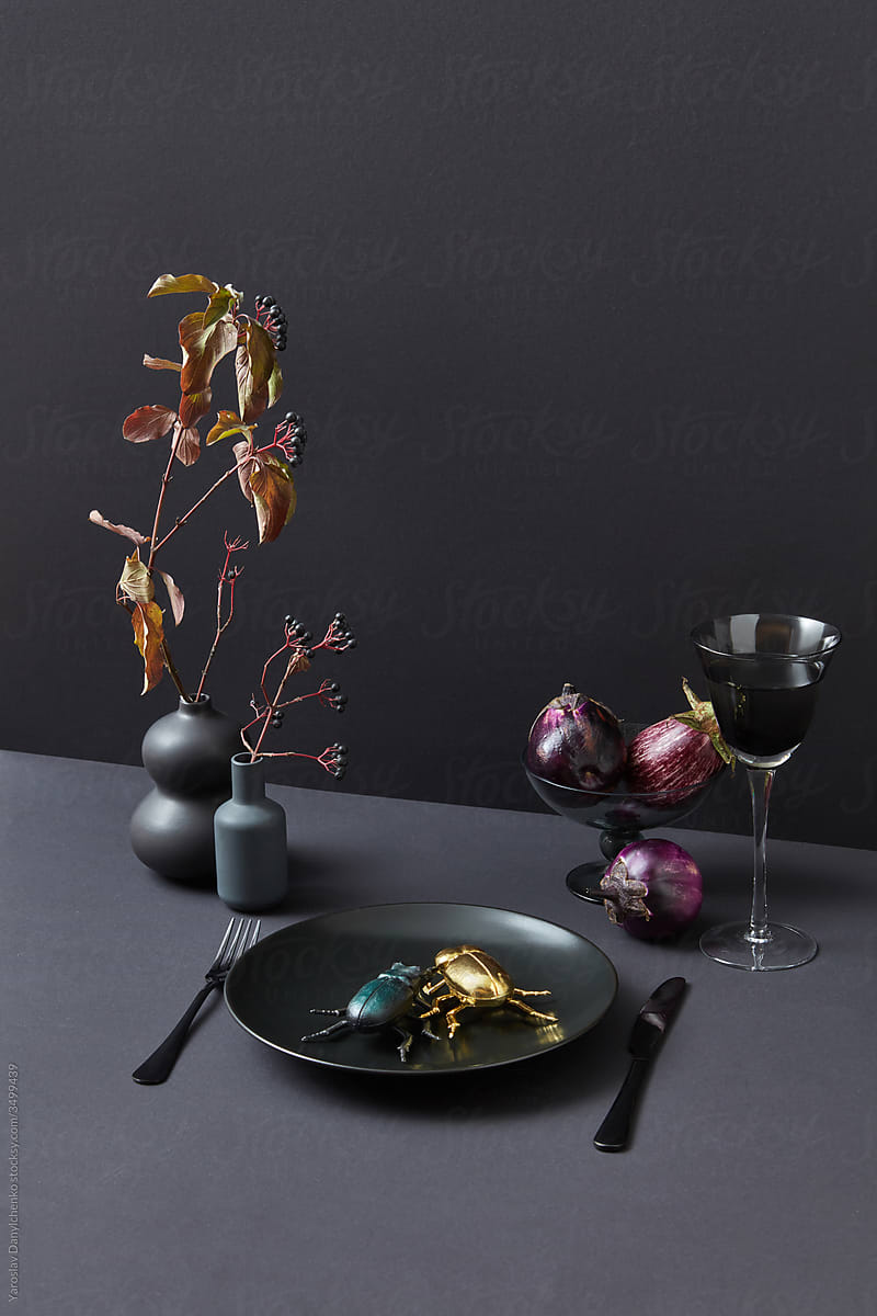 Set with horned bugs in a ceramic plate and eggplants.