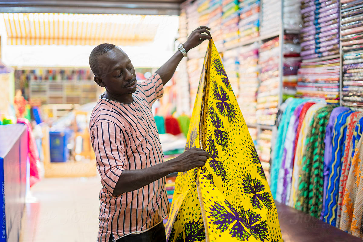 Black salesman folding bright fabric