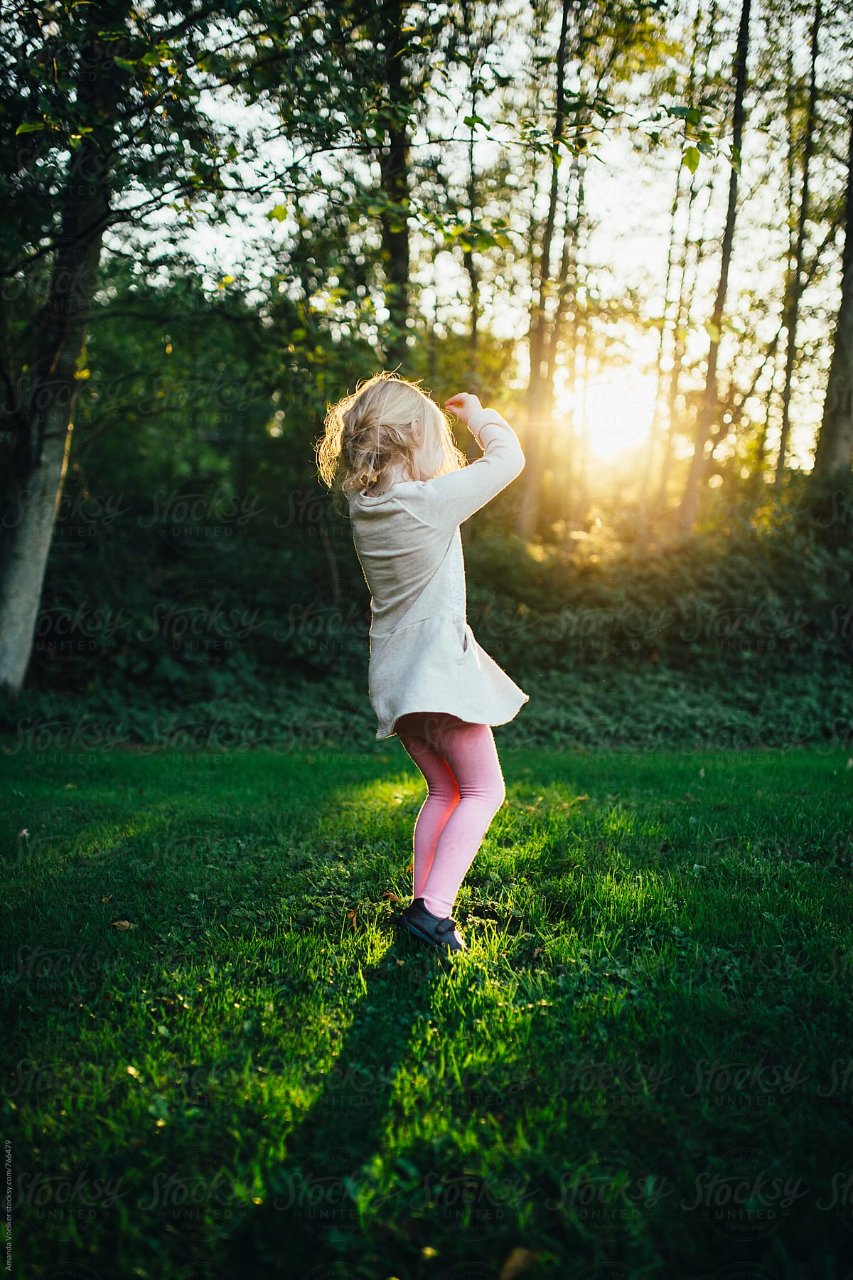 A little girl twirls in the light of the setting sun