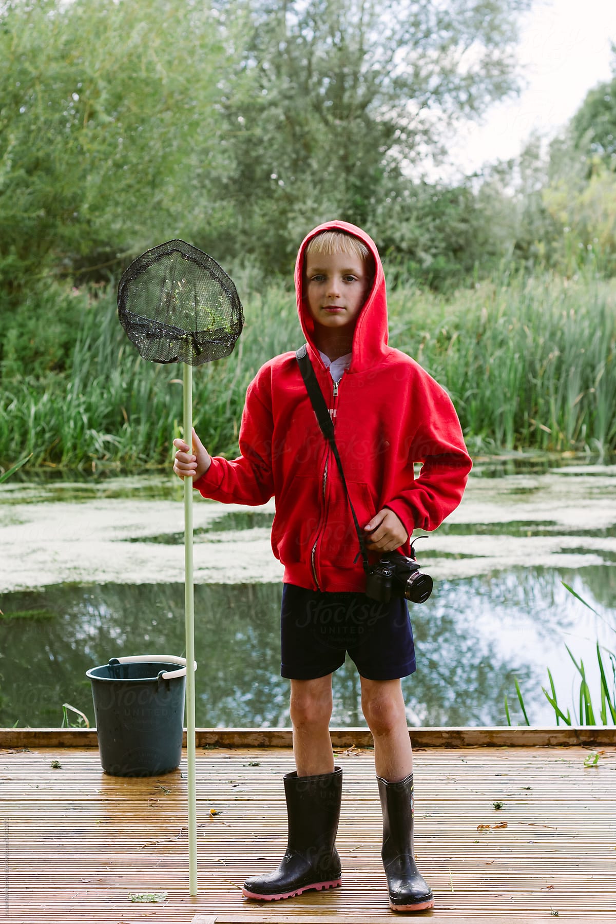 A Young Boy With A Bucket And Fishing Net About To Go Pond Dipping