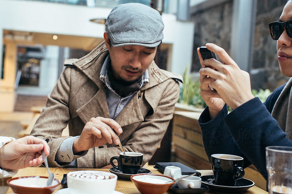 Two Good-Looking Young Asian Men Having Coffee in Bright Café