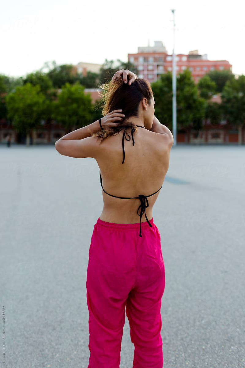 Back of fit sporty girl outdoors tying her hair