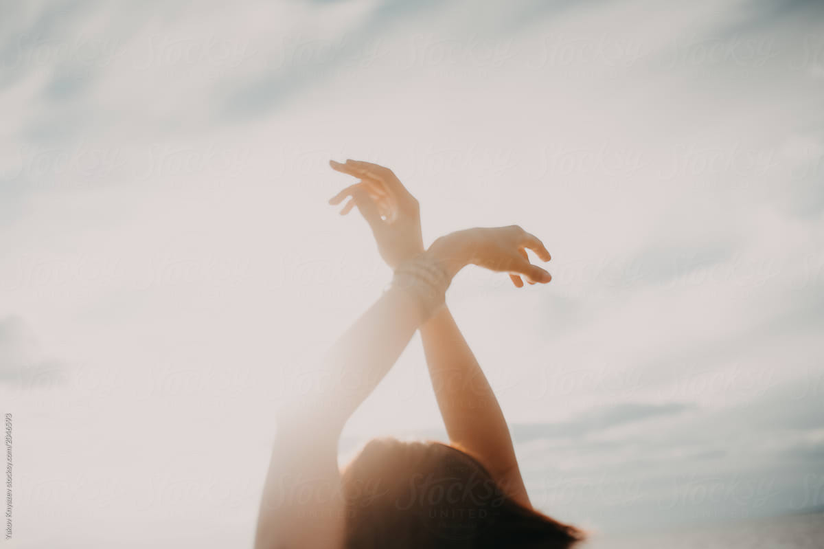 young woman rises hands toward the sun