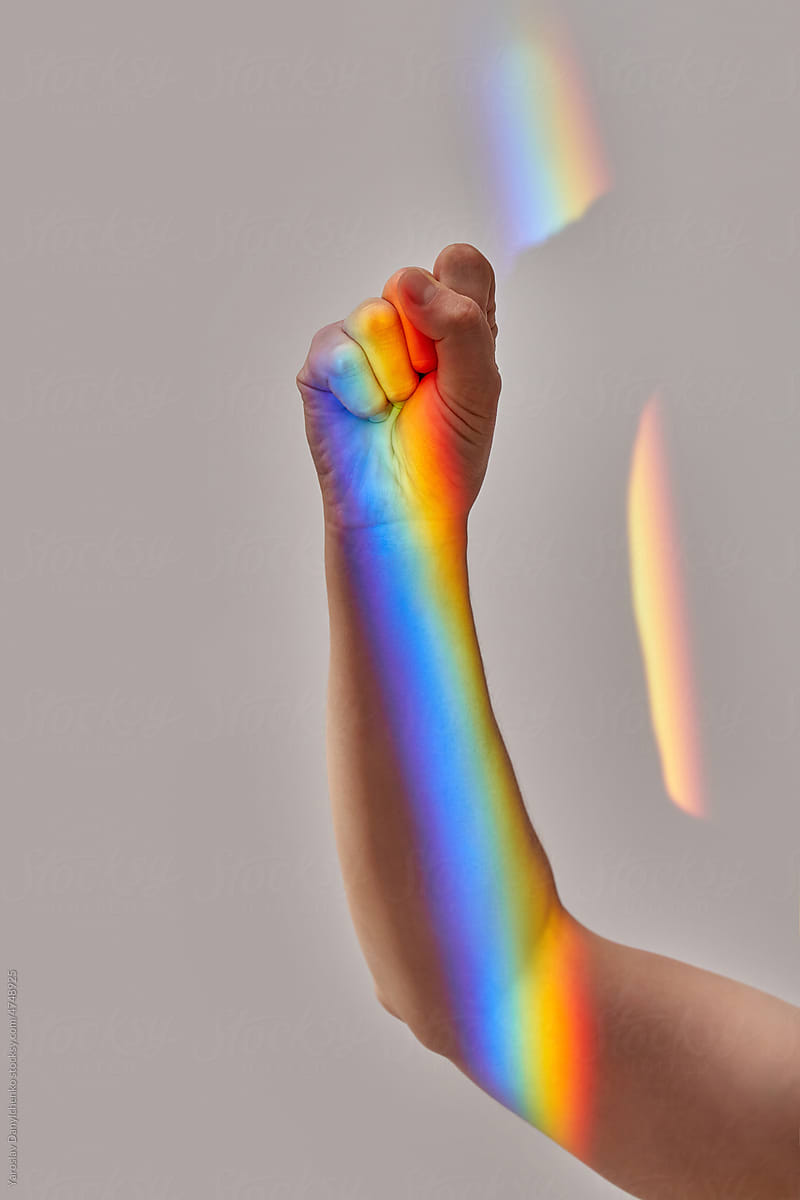 Rainbow overlay over woman's clenched fist.