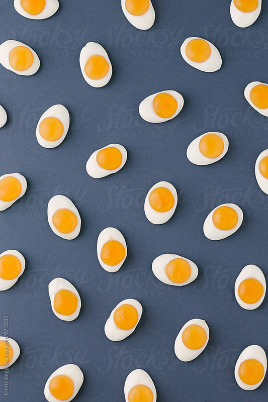 Candy fried eggs in pattern from above on blue