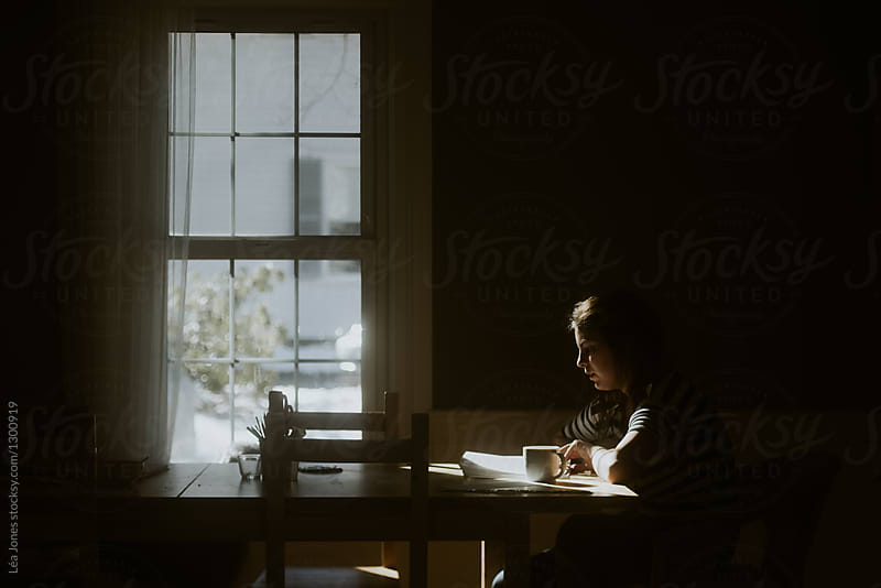 teen studying in window light