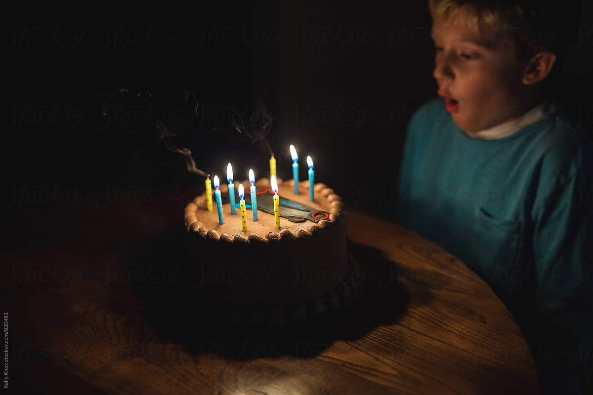 boy blowing out the candles on a birthday cake