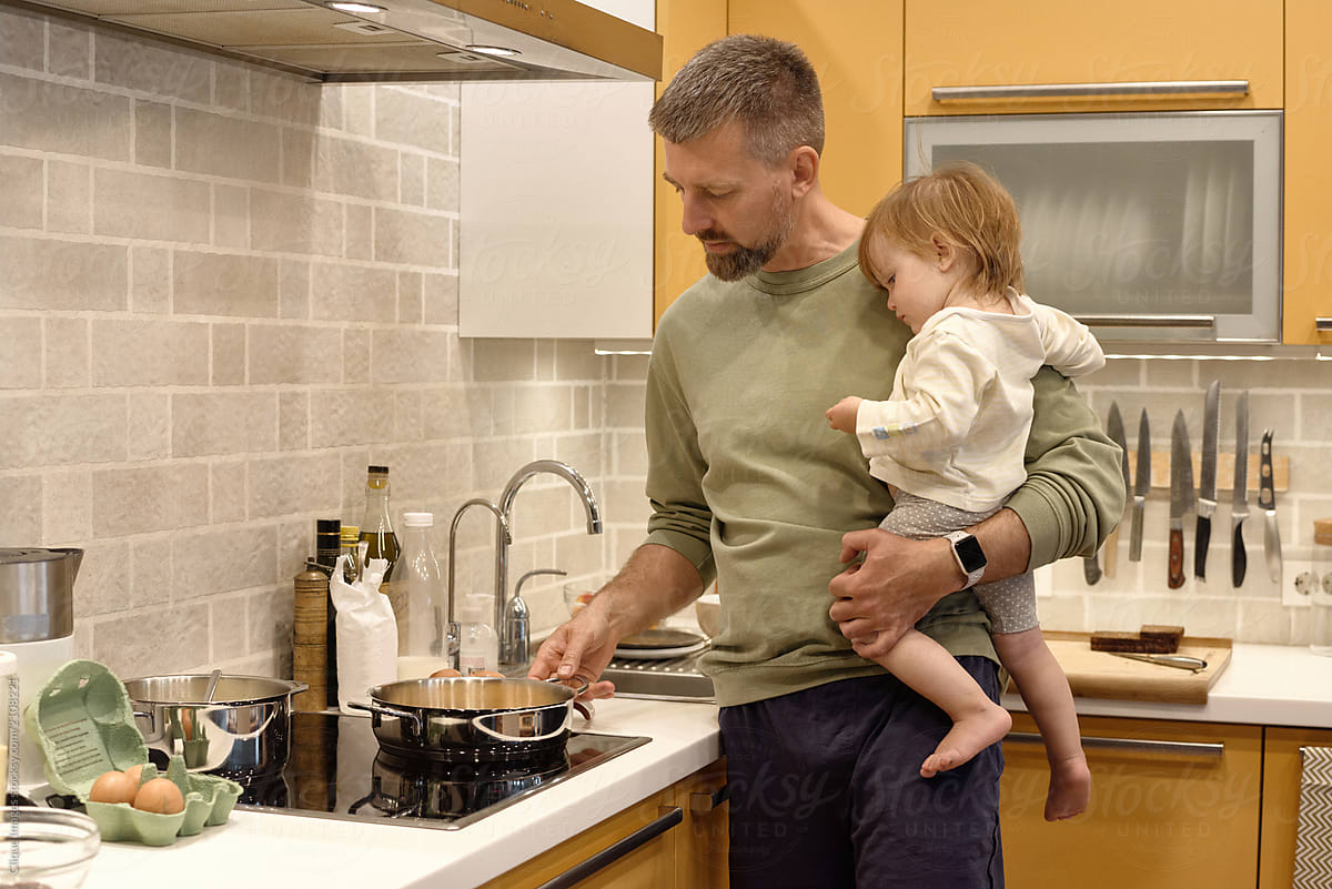 Man with baby on hands cooking meal