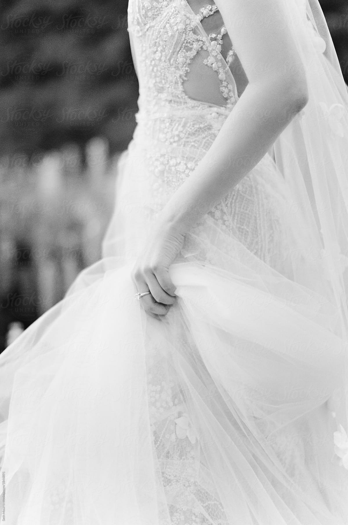 A bride delicately holds her wedding gown