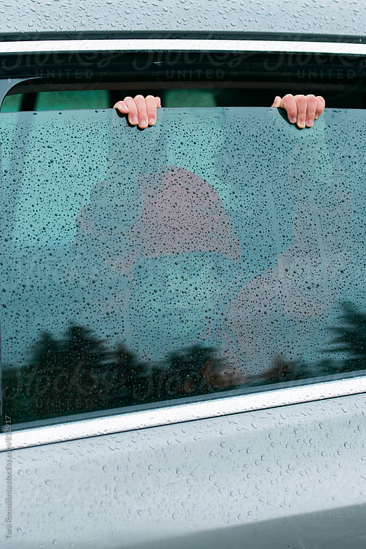 child looking outside a car window on a rainy day