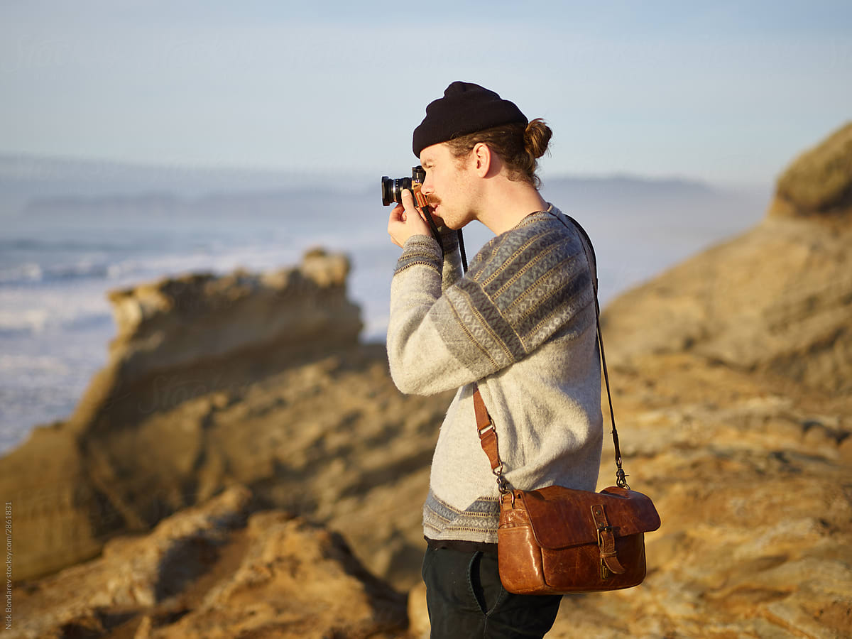Male traveler taking pictures on seashore