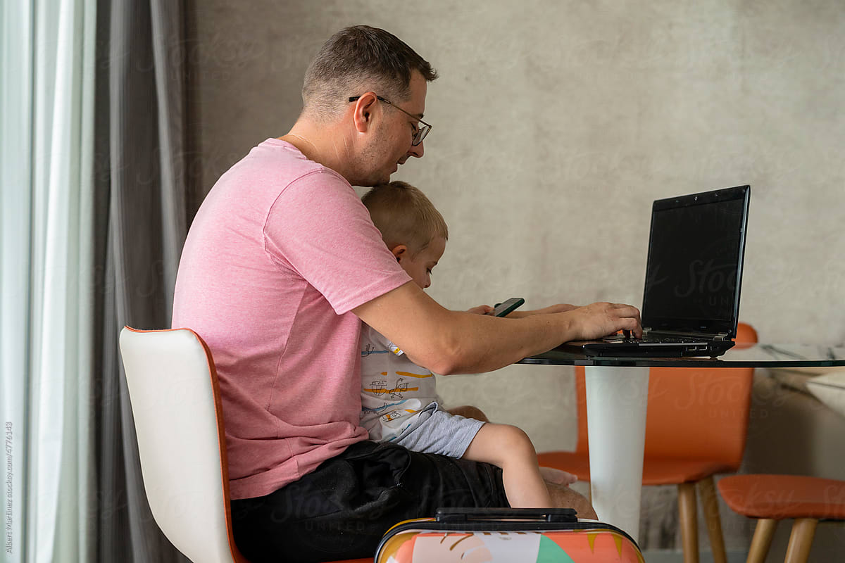 Man in a hotel with his son working with his laptop in the room