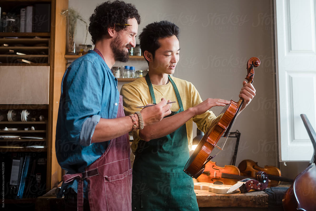 Two young luthiers analysing an old violin