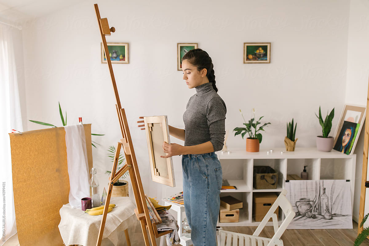 Young woman holding painting in art studio