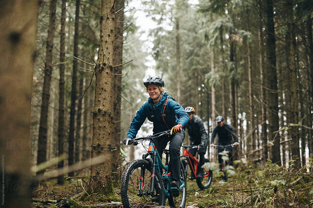 Smiling woman mountain biking in a forest with friends