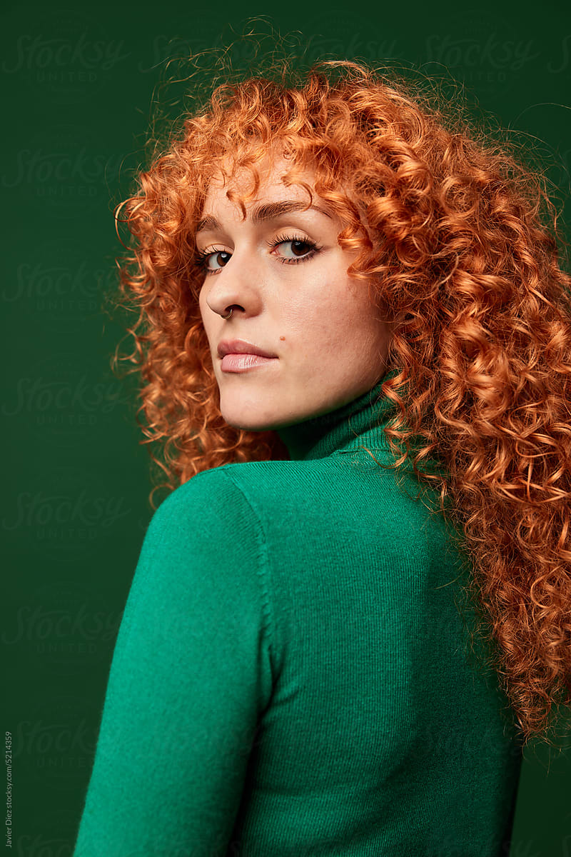 Confident young ginger woman on green background